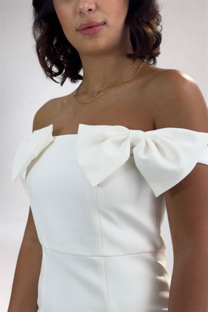 White off-shoulder dress with bow details on a plain background