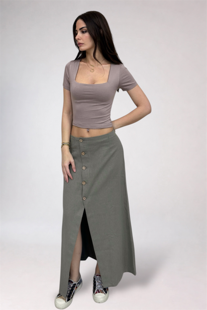 Woman wearing a brown crop top and long gray skirt on a white background