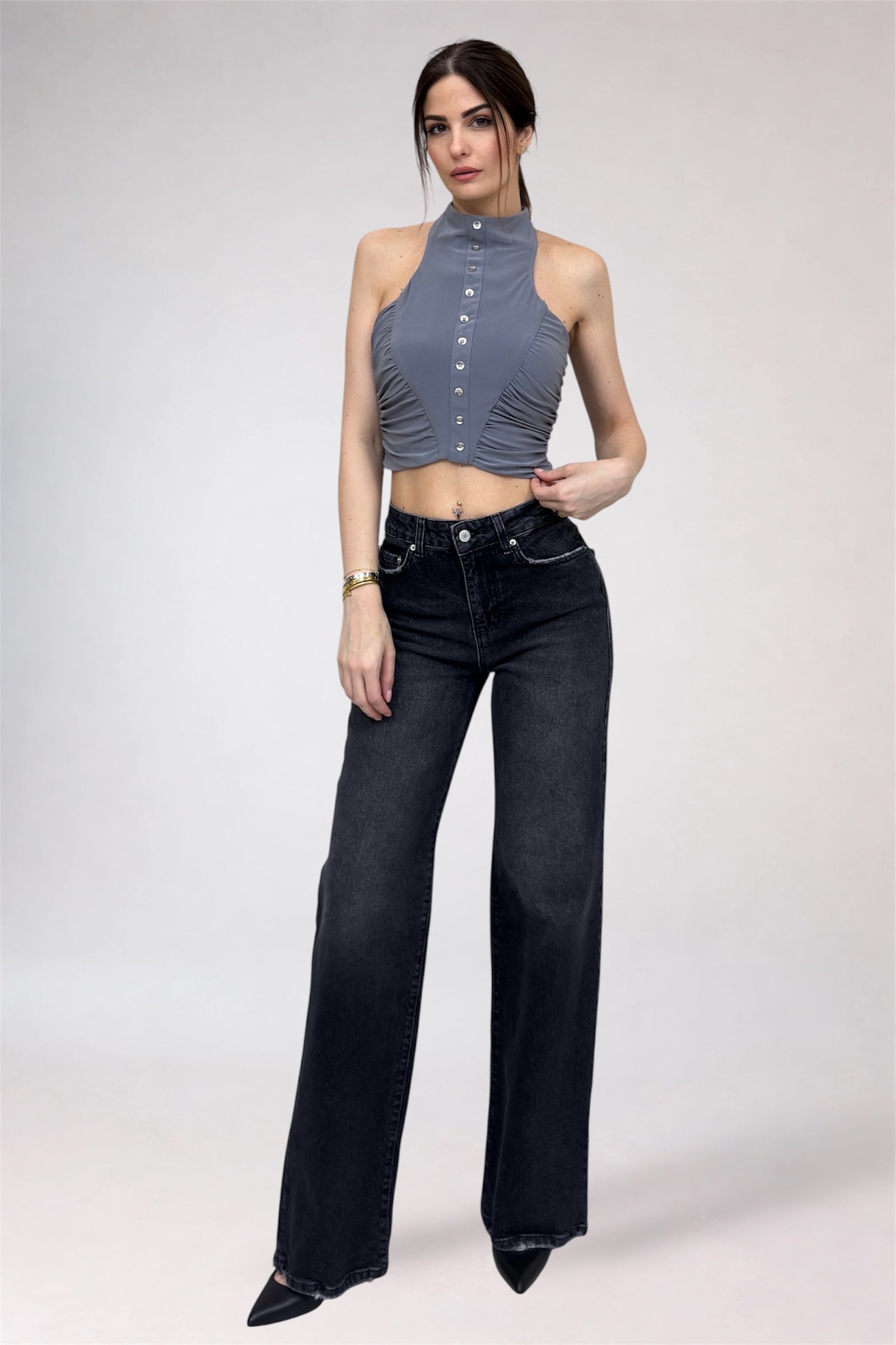 Woman wearing a gray halter top and black high-waisted jeans on a white background