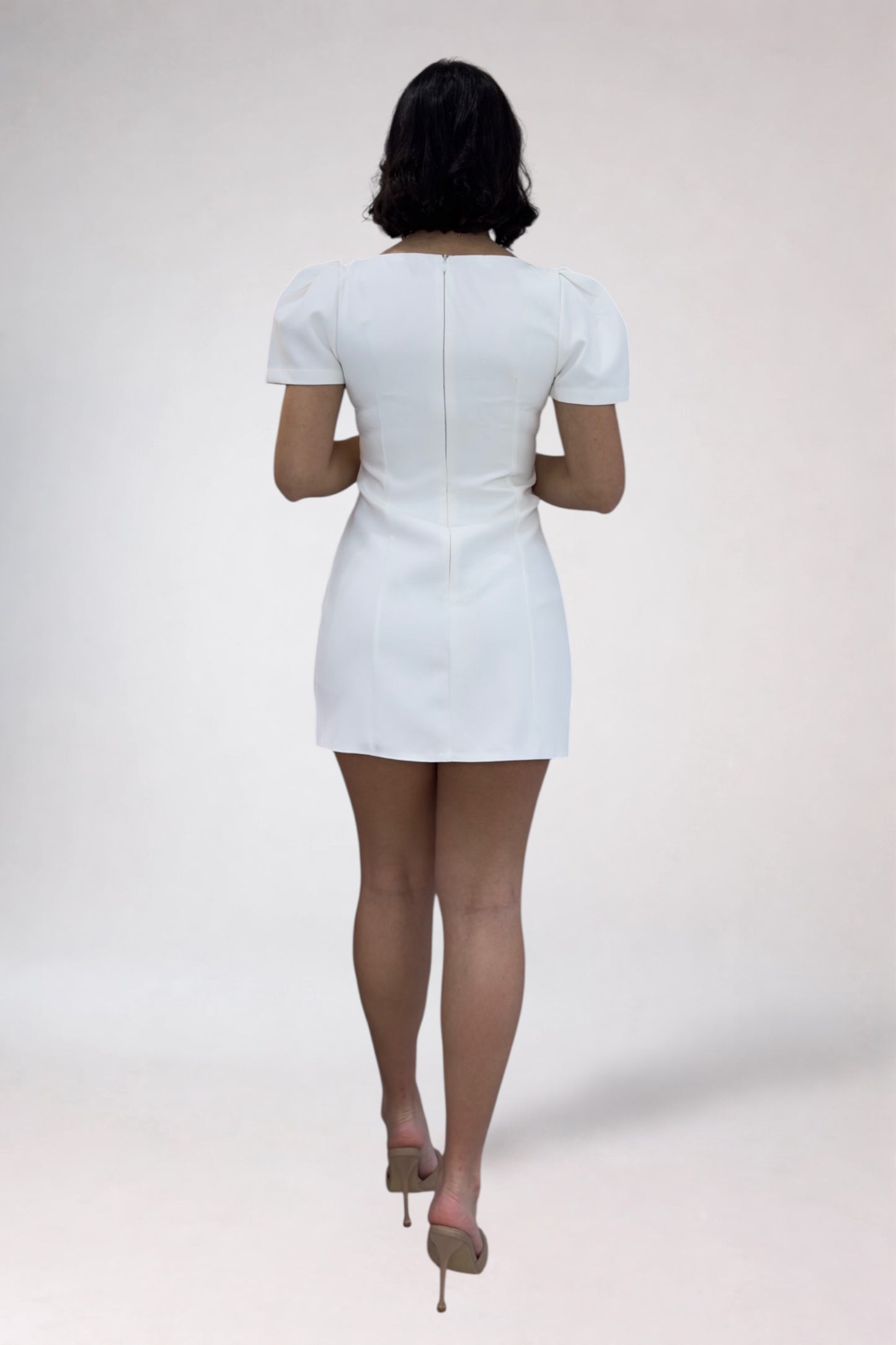 Person wearing a white dress on a plain background