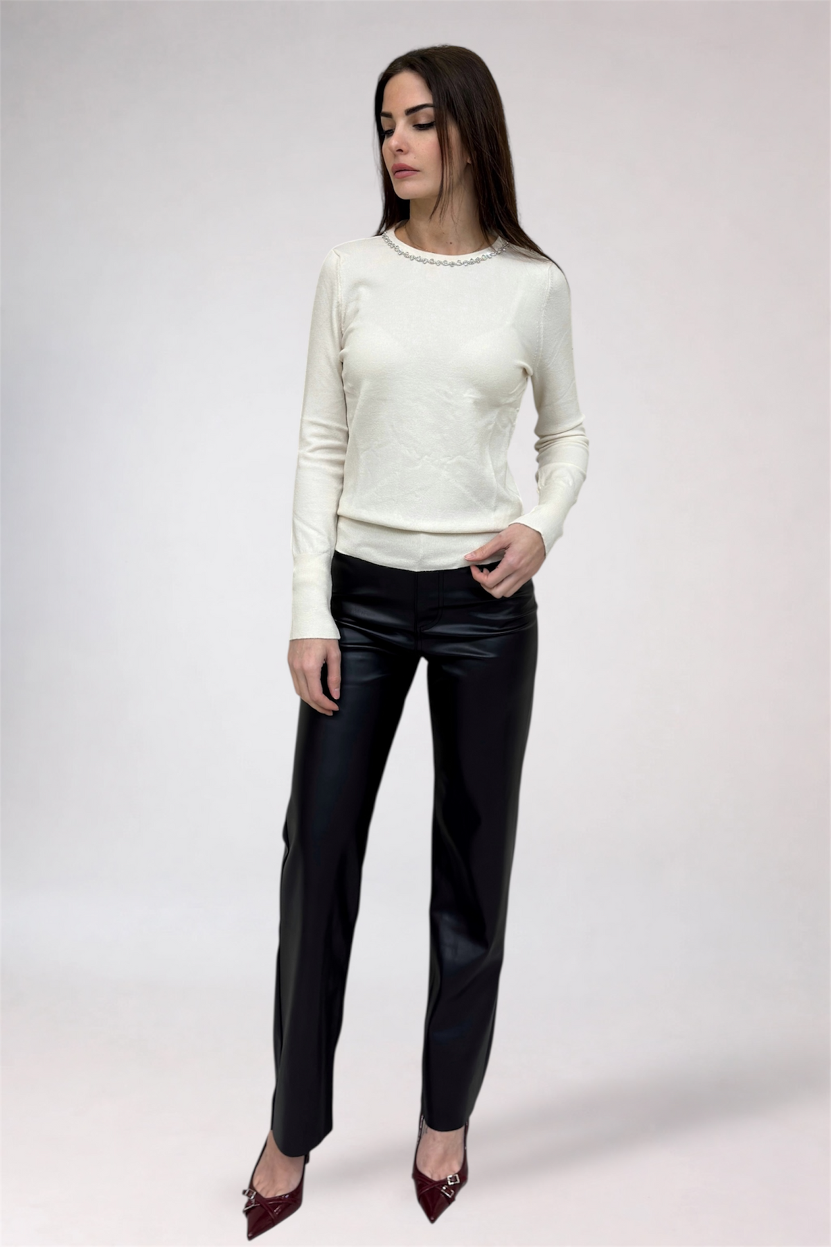 Woman wearing a white sweater and black pants on a white background