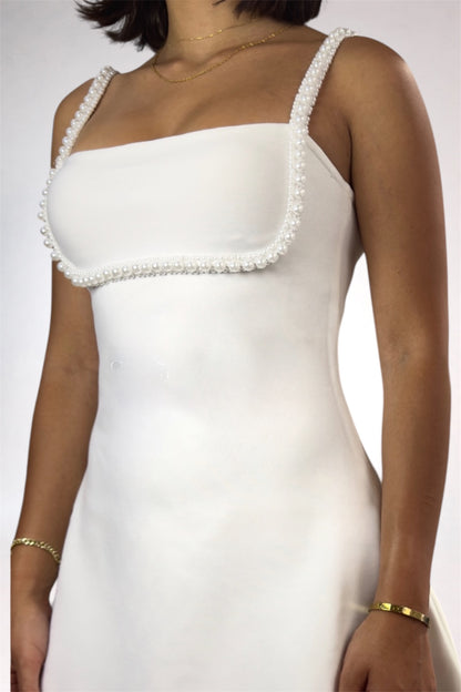 White dress with pearl embellishments on a plain background
