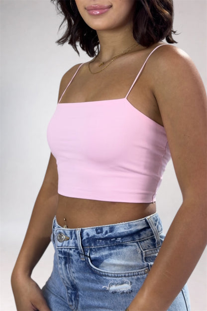 Person wearing a pink crop top and blue jeans on a plain background