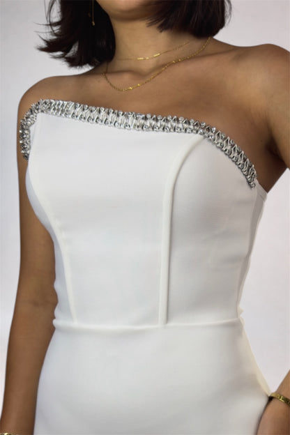 White dress with embellished neckline on a plain background