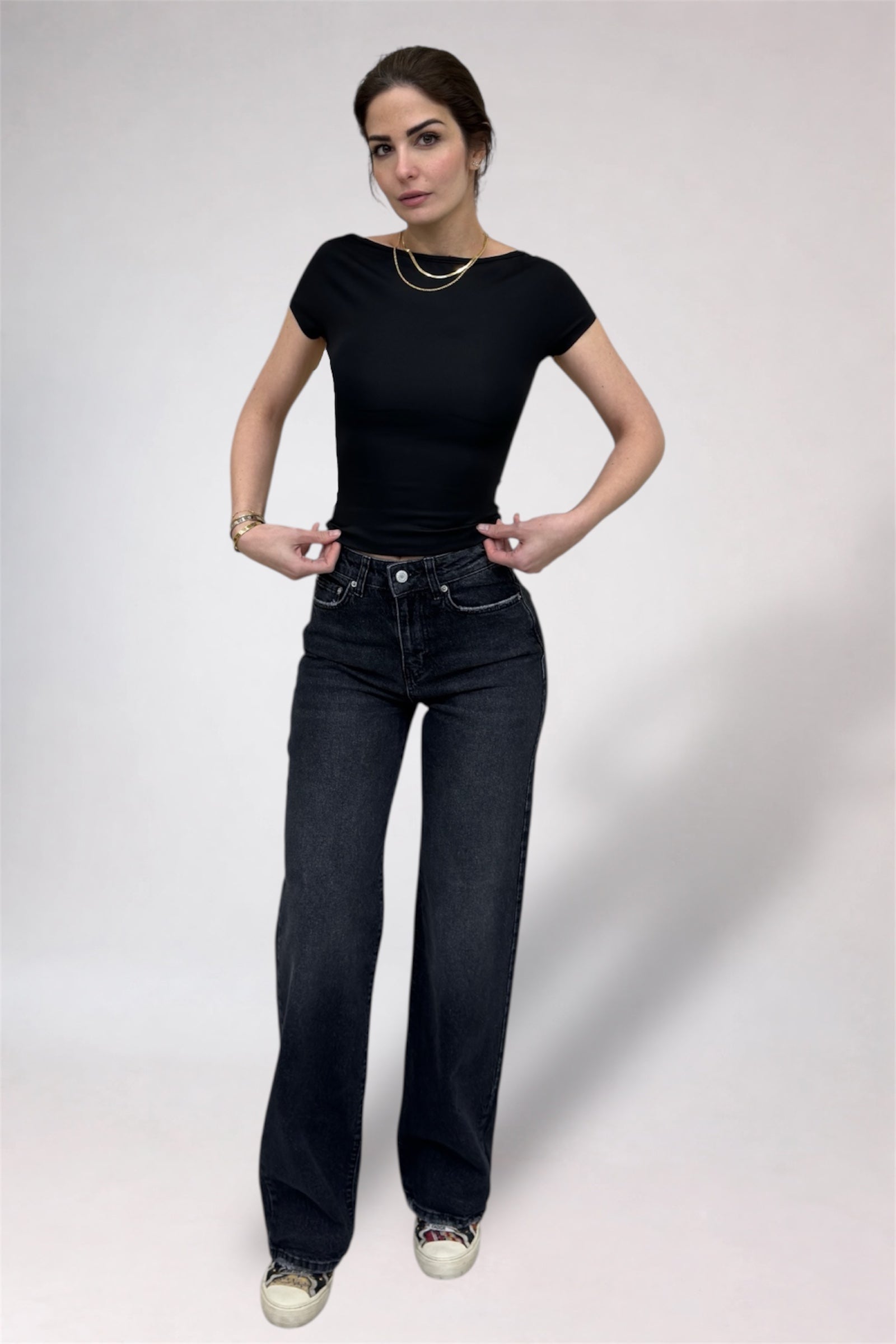 Woman wearing a black t-shirt and dark jeans on a white background