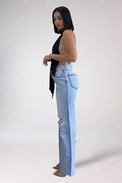 Woman wearing light blue jeans with a black top on a white background