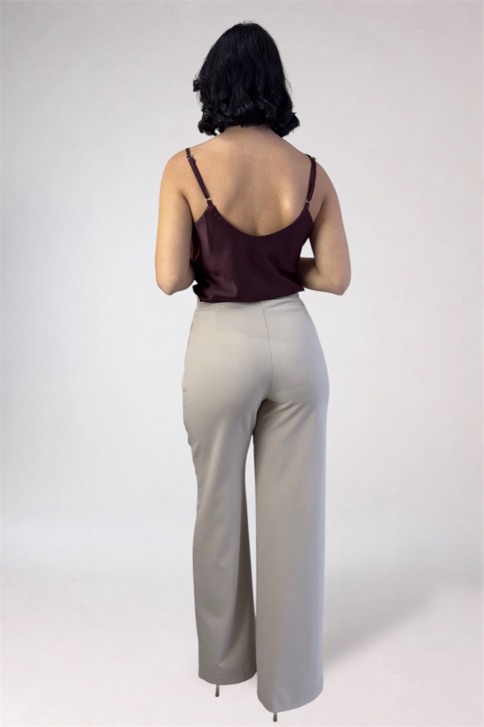 Person wearing a burgundy top and beige pants on a white background