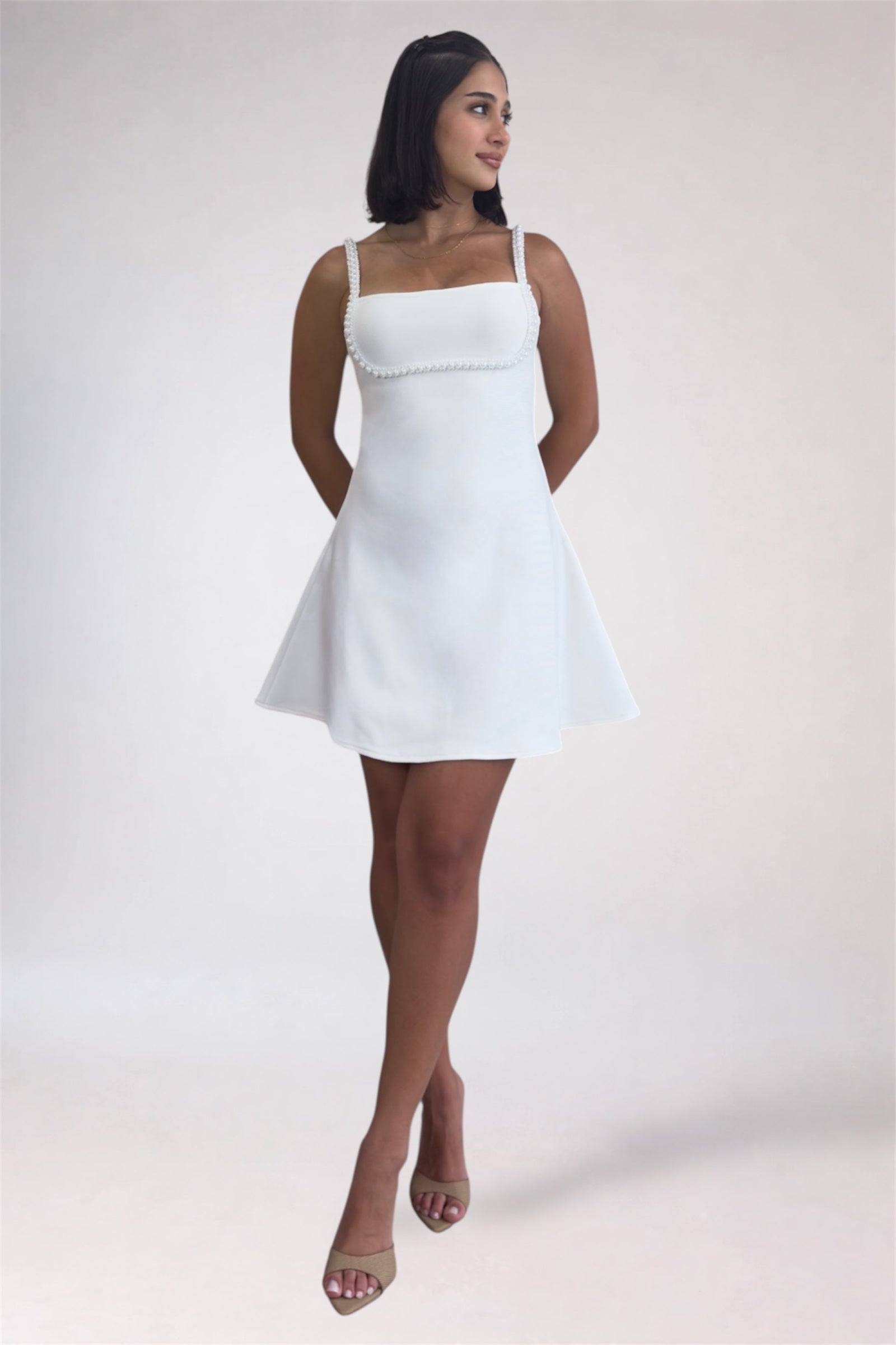 Woman wearing a white dress against a plain background
