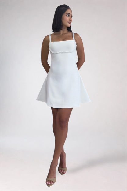 Woman wearing a white dress against a plain background