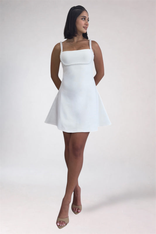 Woman wearing a white dress against a plain background