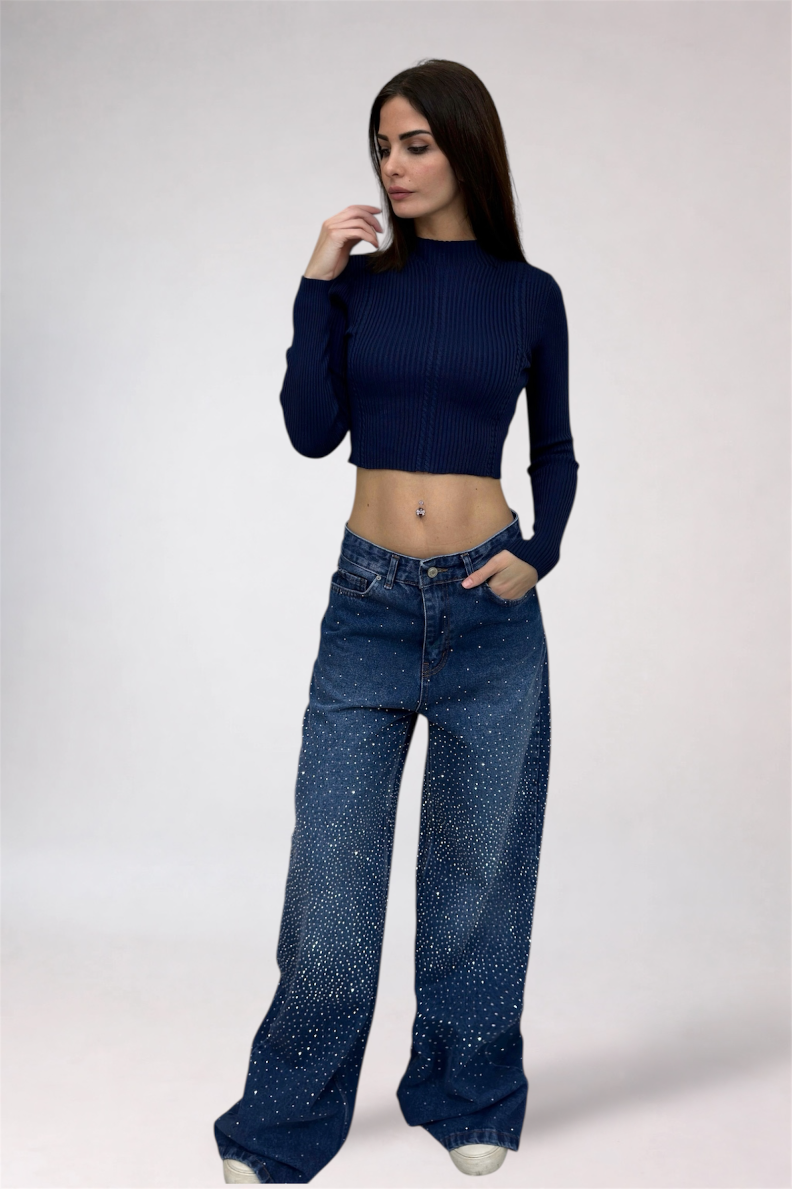 Woman wearing a dark blue ribbed top and wide-leg jeans on a white background