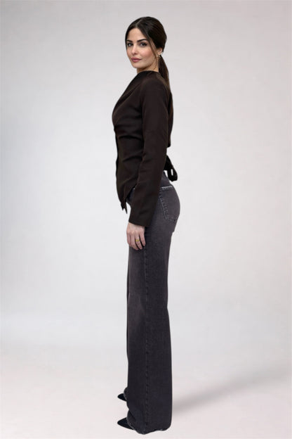 Woman wearing a black top and dark jeans on a white background