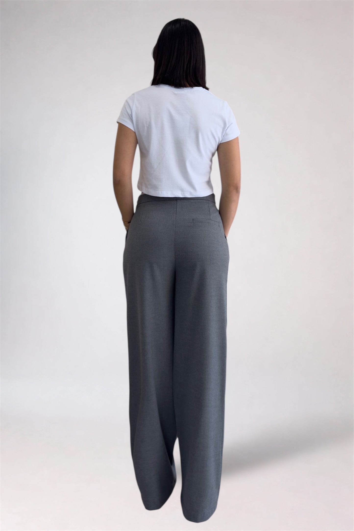 Person wearing a white t-shirt and gray wide-leg pants on a plain background