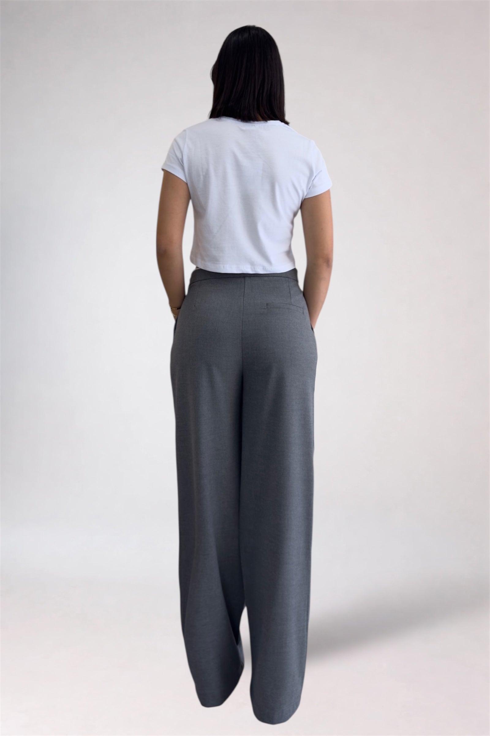 Person wearing a white t-shirt and gray wide-leg pants on a plain background