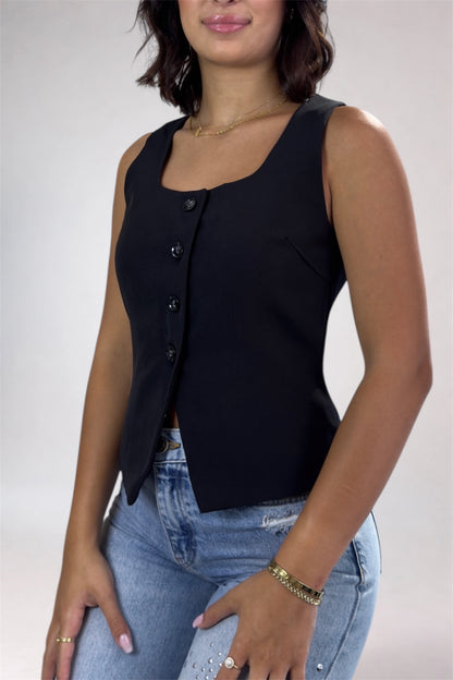 Woman wearing a black sleeveless top and blue jeans against a plain background