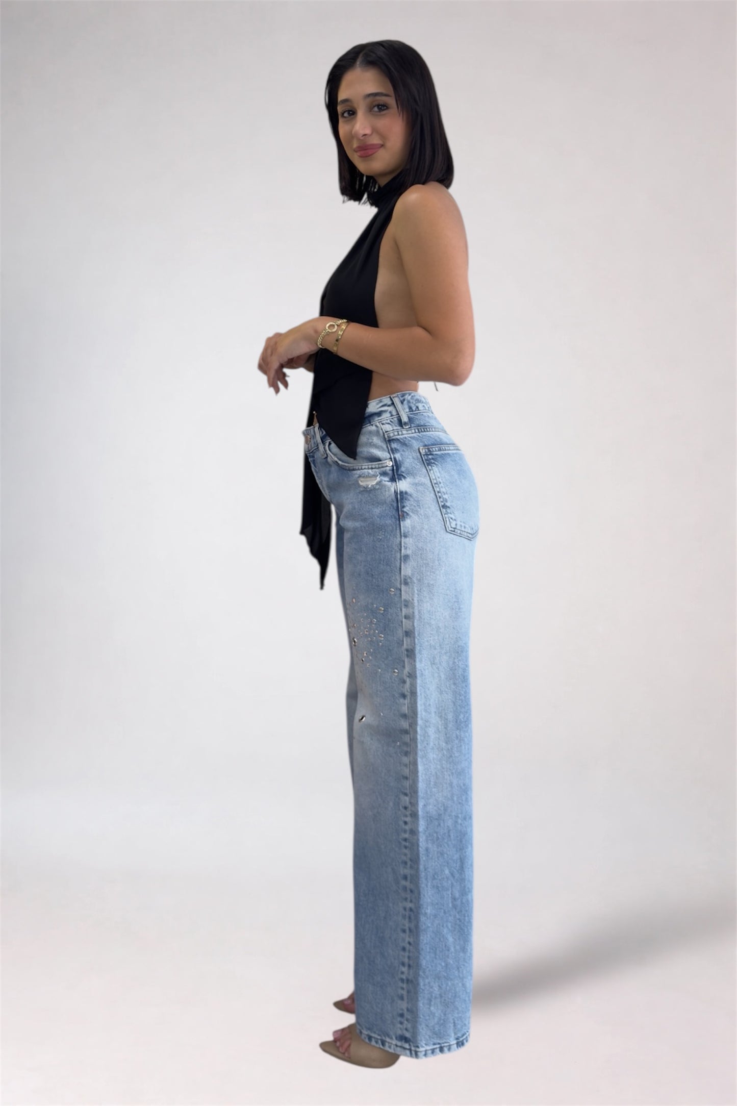 Woman wearing light blue jeans and a black top on a white background