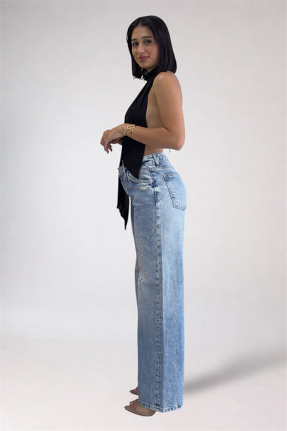Woman wearing light blue jeans and a black top on a white background