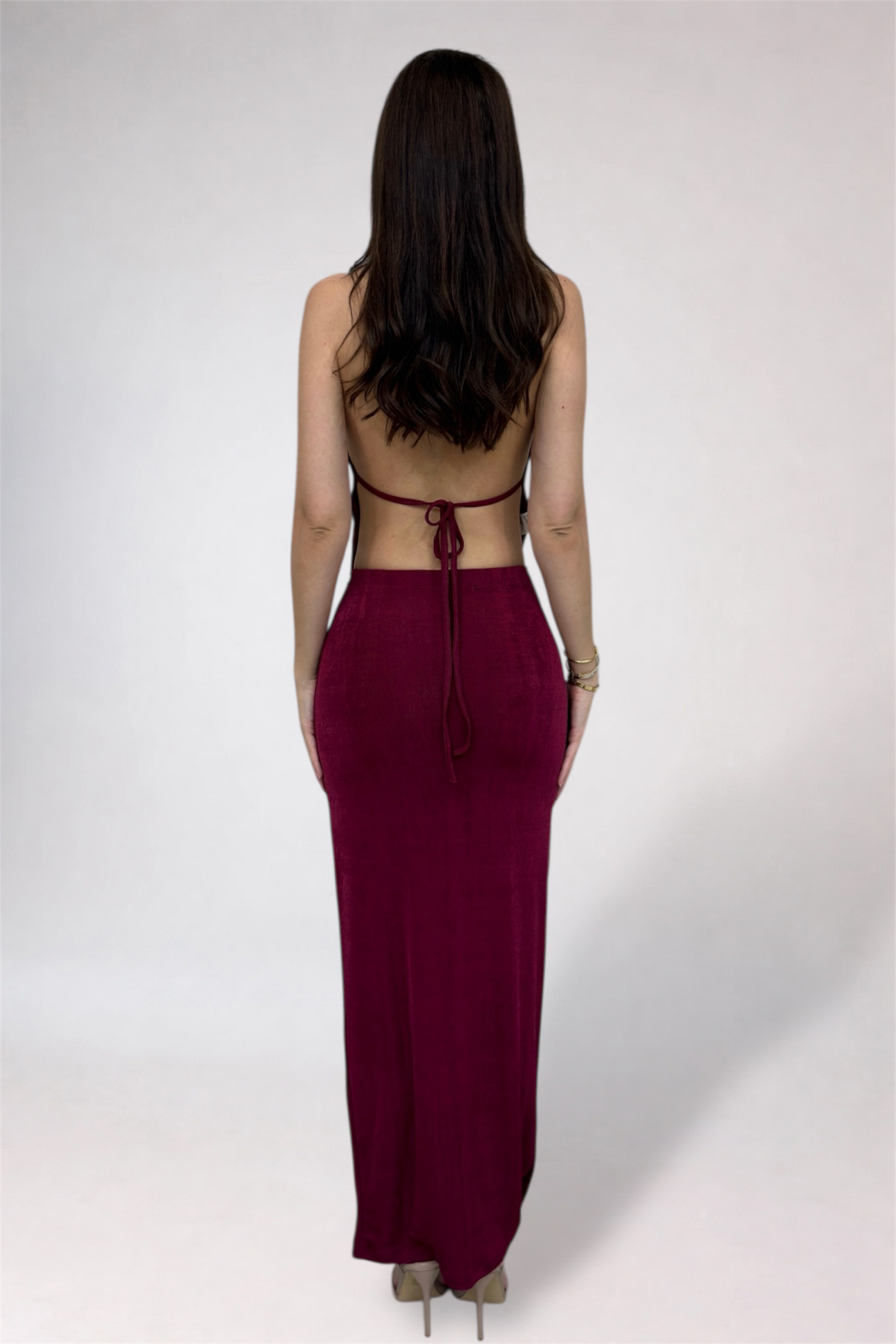 Woman wearing a burgundy dress with a backless design on a white background