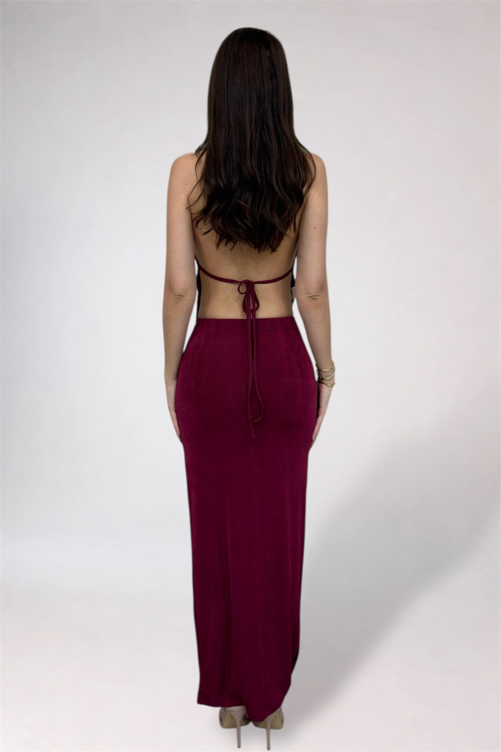 Woman wearing a burgundy dress with a backless design on a white background