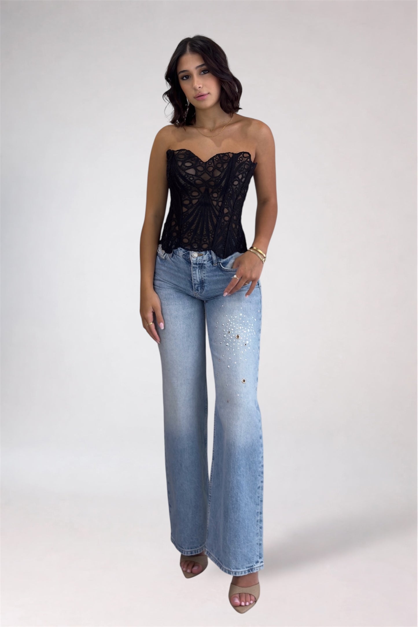 Woman wearing a black lace top and blue jeans on a white background