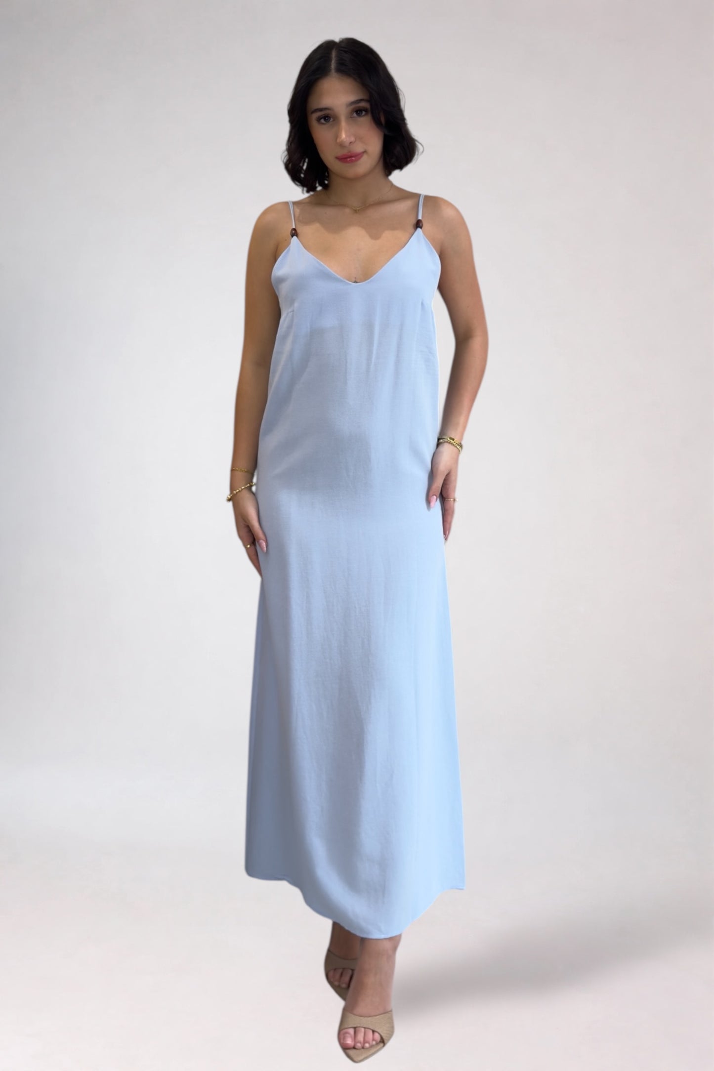 Woman wearing a light blue slip dress on a white background