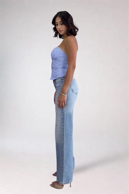 Woman wearing a blue strapless top and jeans on a white background