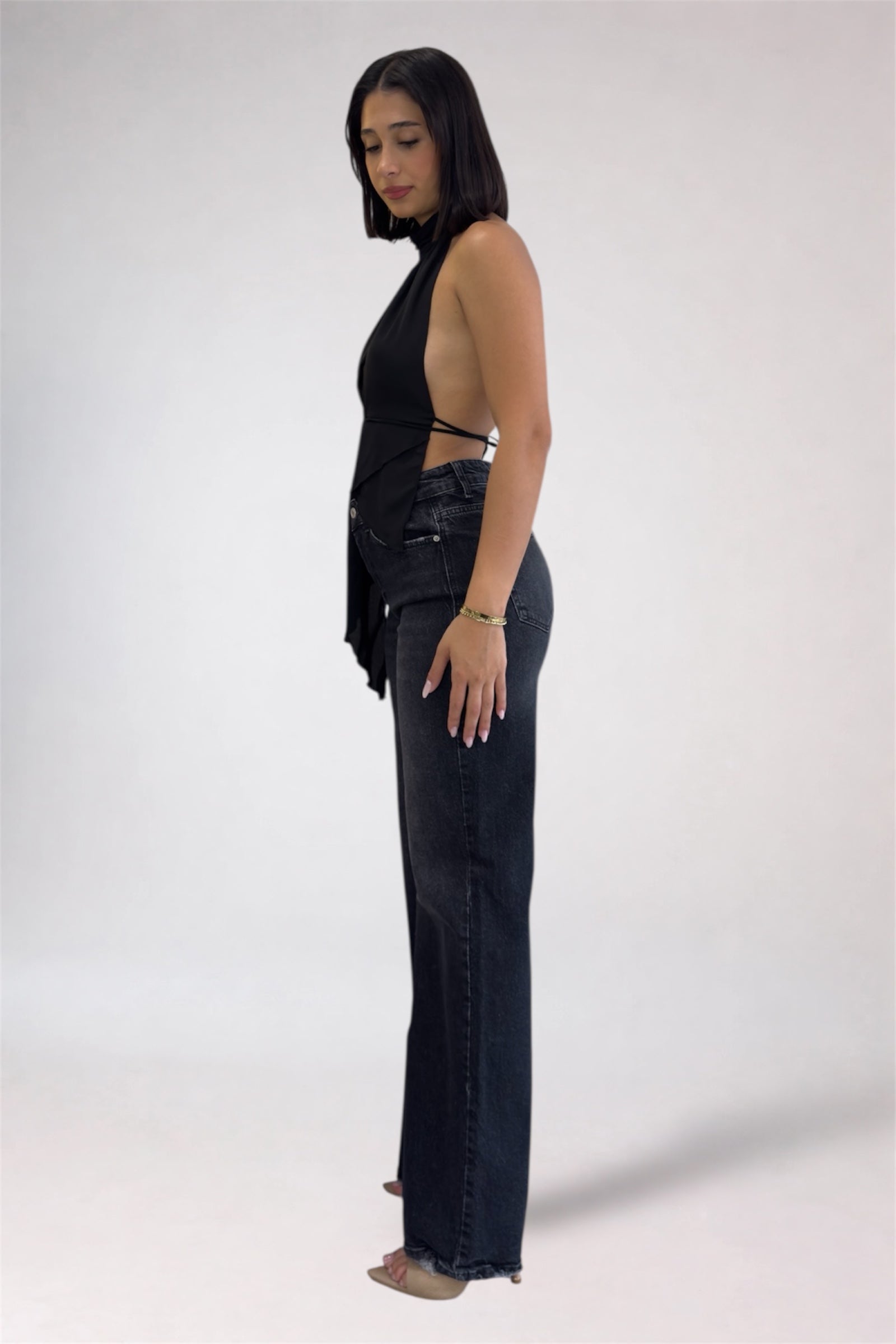 Woman wearing a black sleeveless top and dark blue jeans on a white background