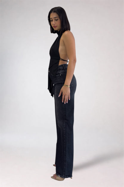 Woman wearing a black sleeveless top and dark blue jeans on a white background