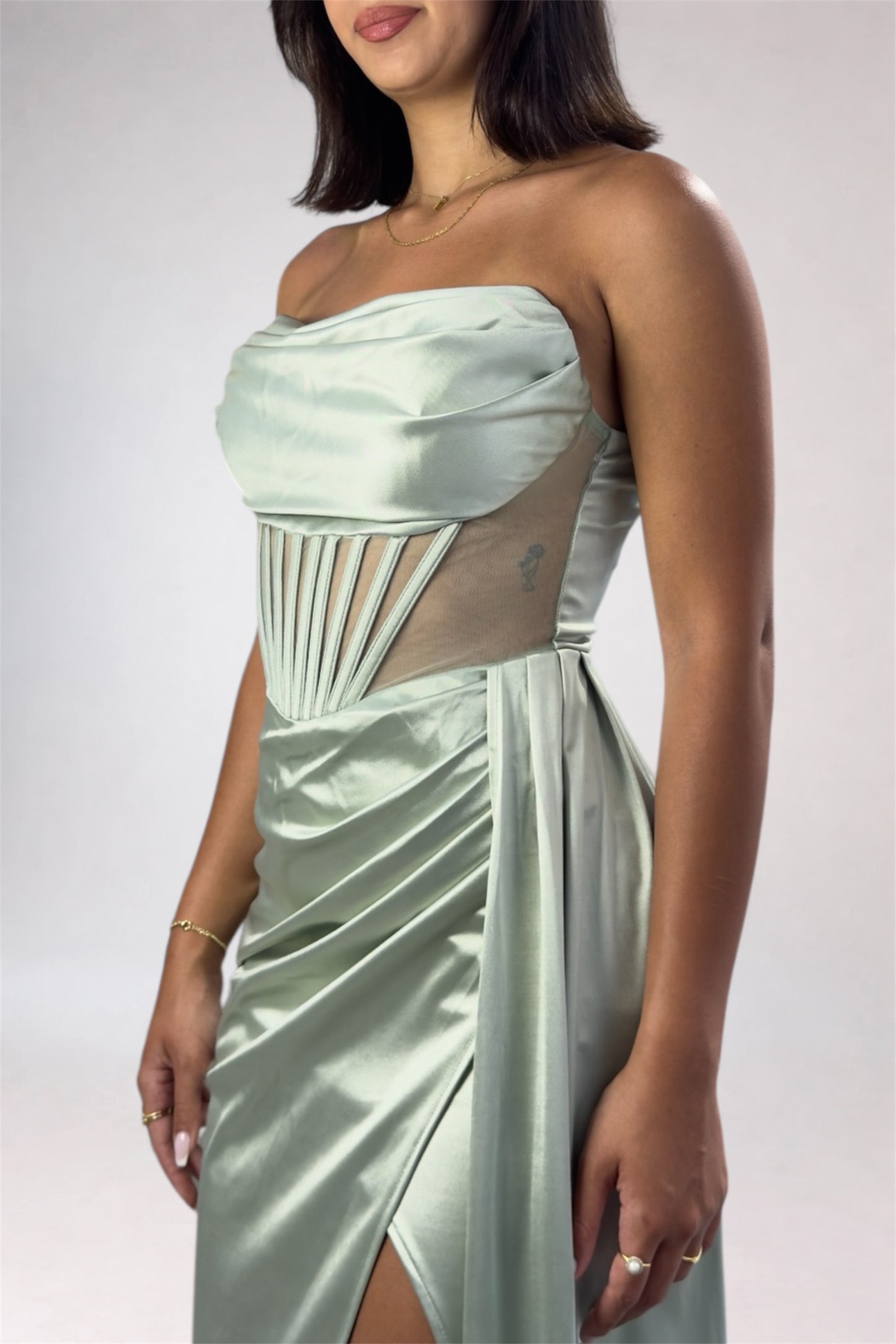 Woman wearing a strapless, light-colored dress with geometric cutouts on a plain background