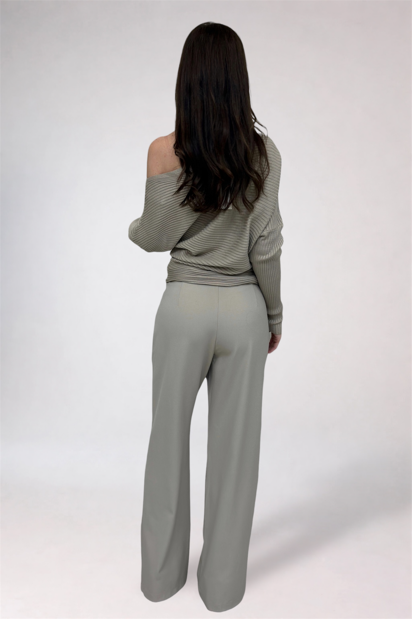 Person wearing a gray off-shoulder top and wide-leg pants on a white background