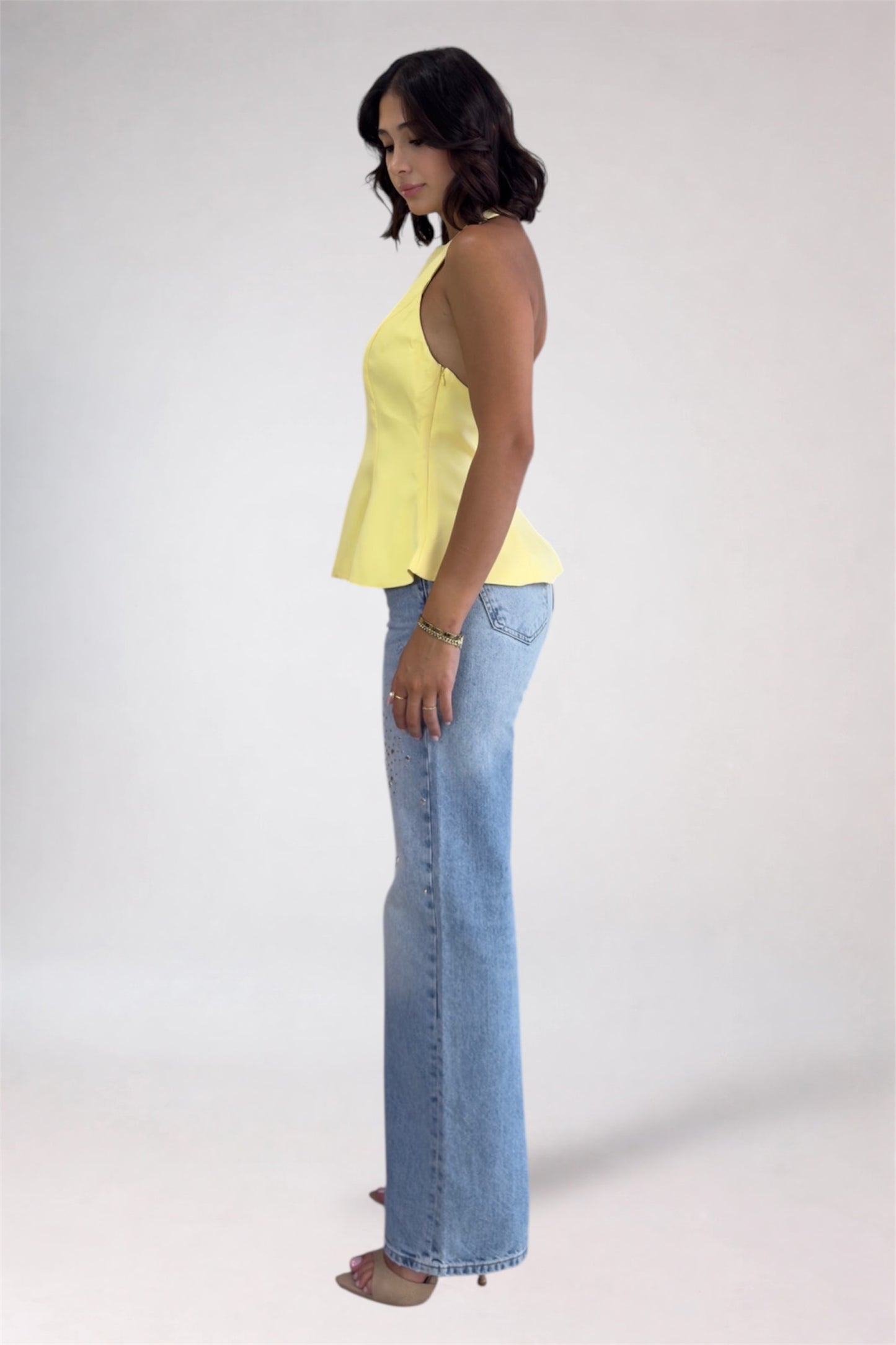 Woman wearing a yellow top and blue jeans on a white background