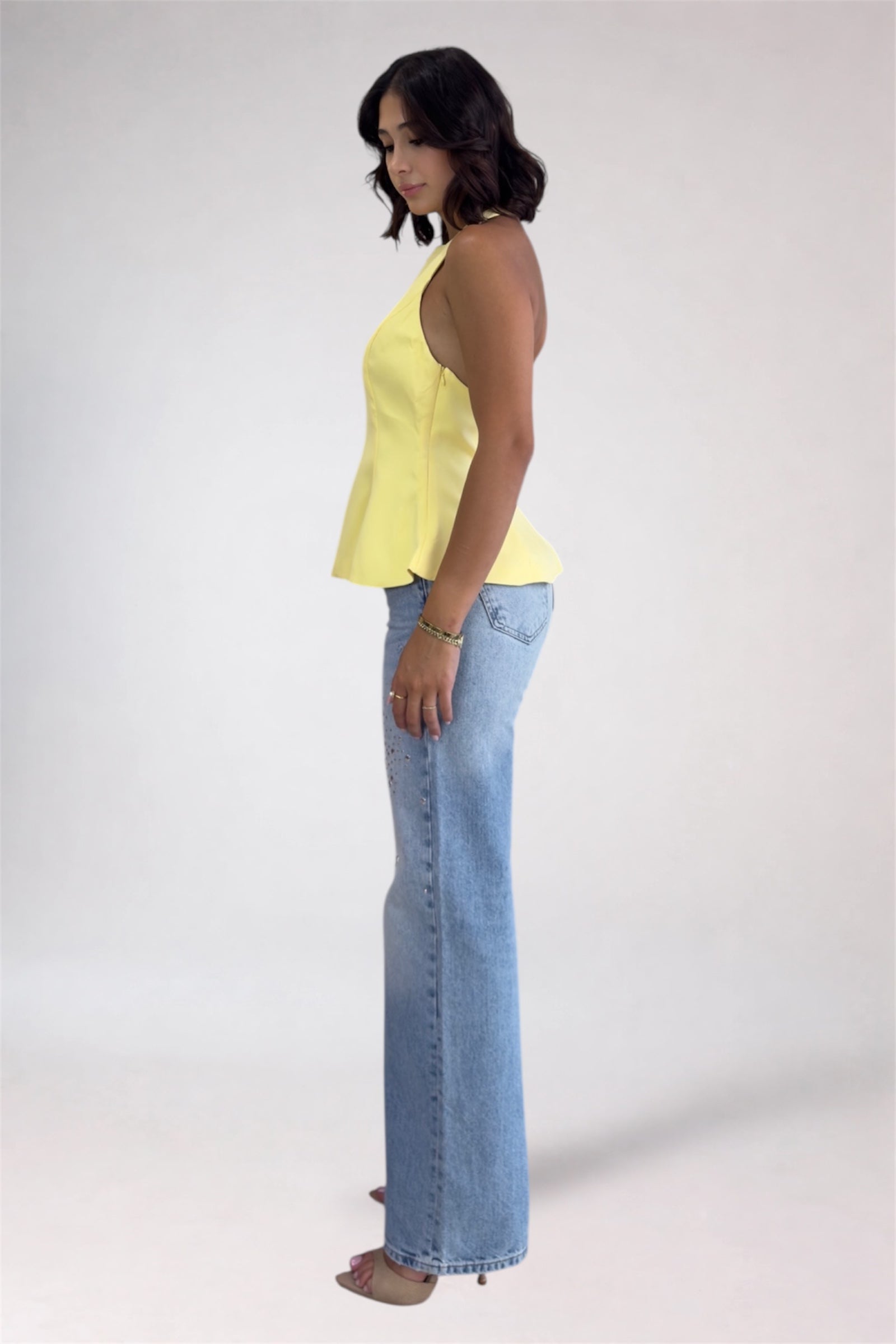 Woman wearing a yellow top and blue jeans on a white background