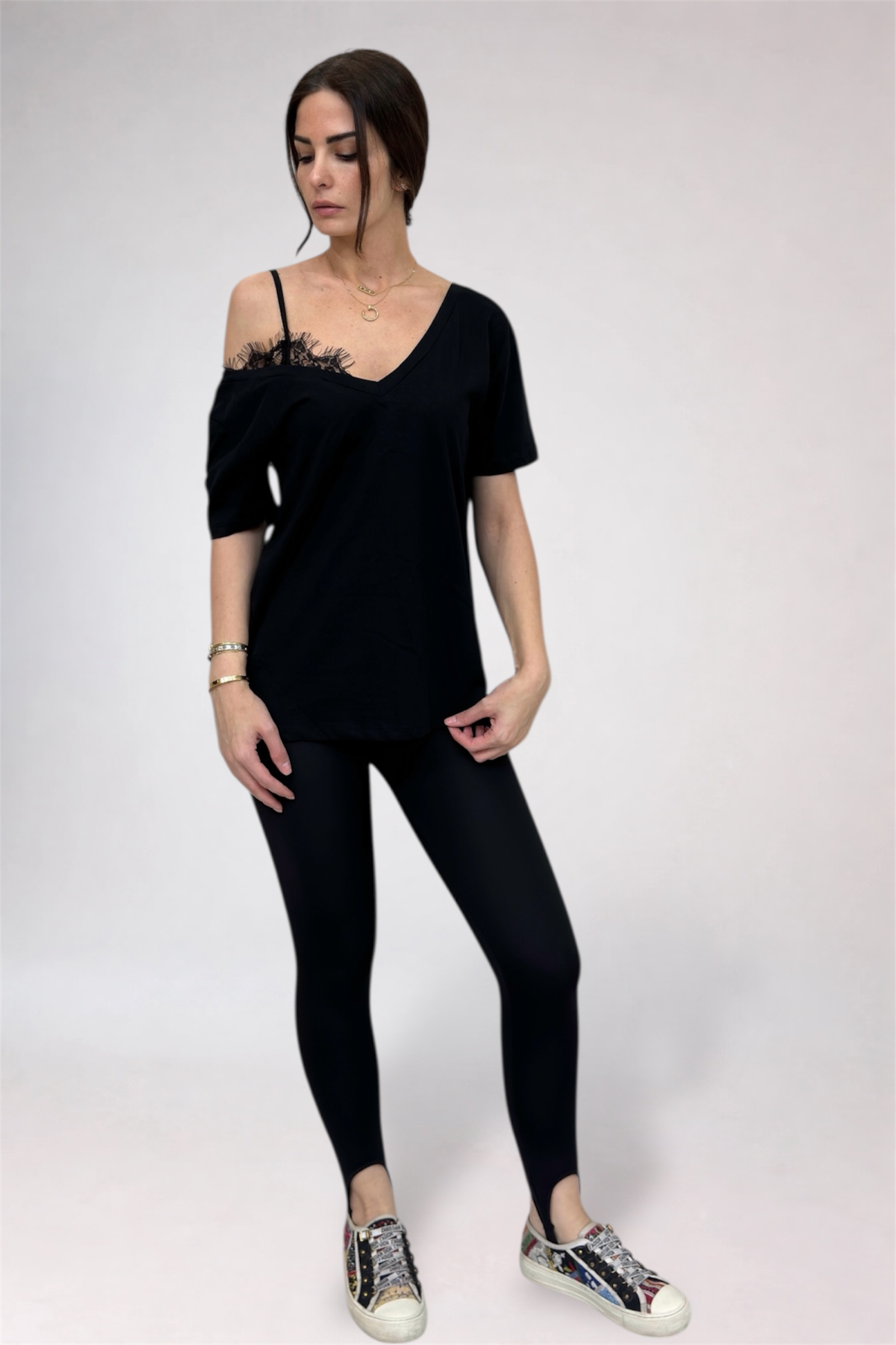 Woman wearing a black off-shoulder top and leggings on a white background