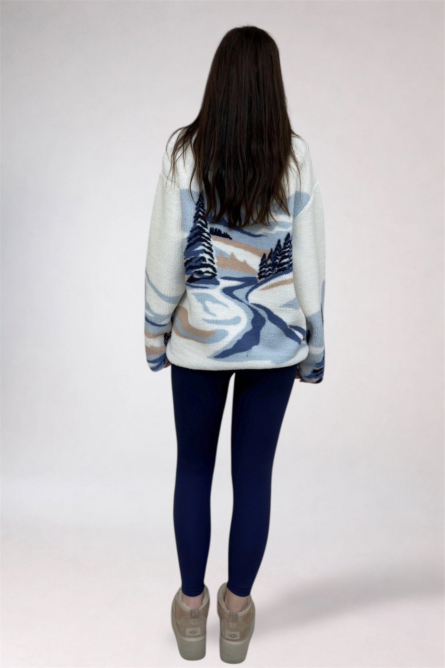 Person wearing a patterned sweater with a scenic design on a plain background