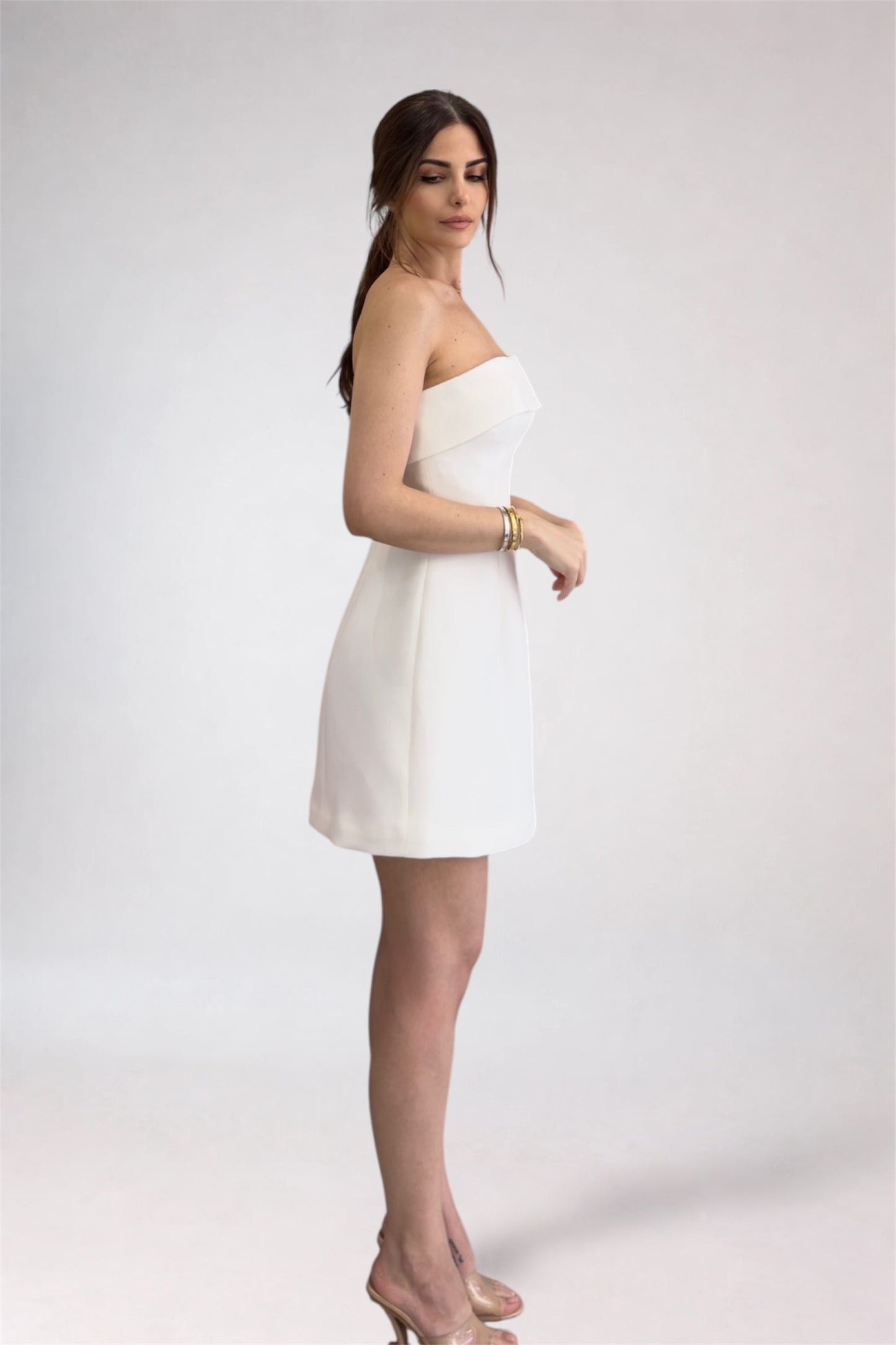 Woman wearing a white strapless dress on a plain background