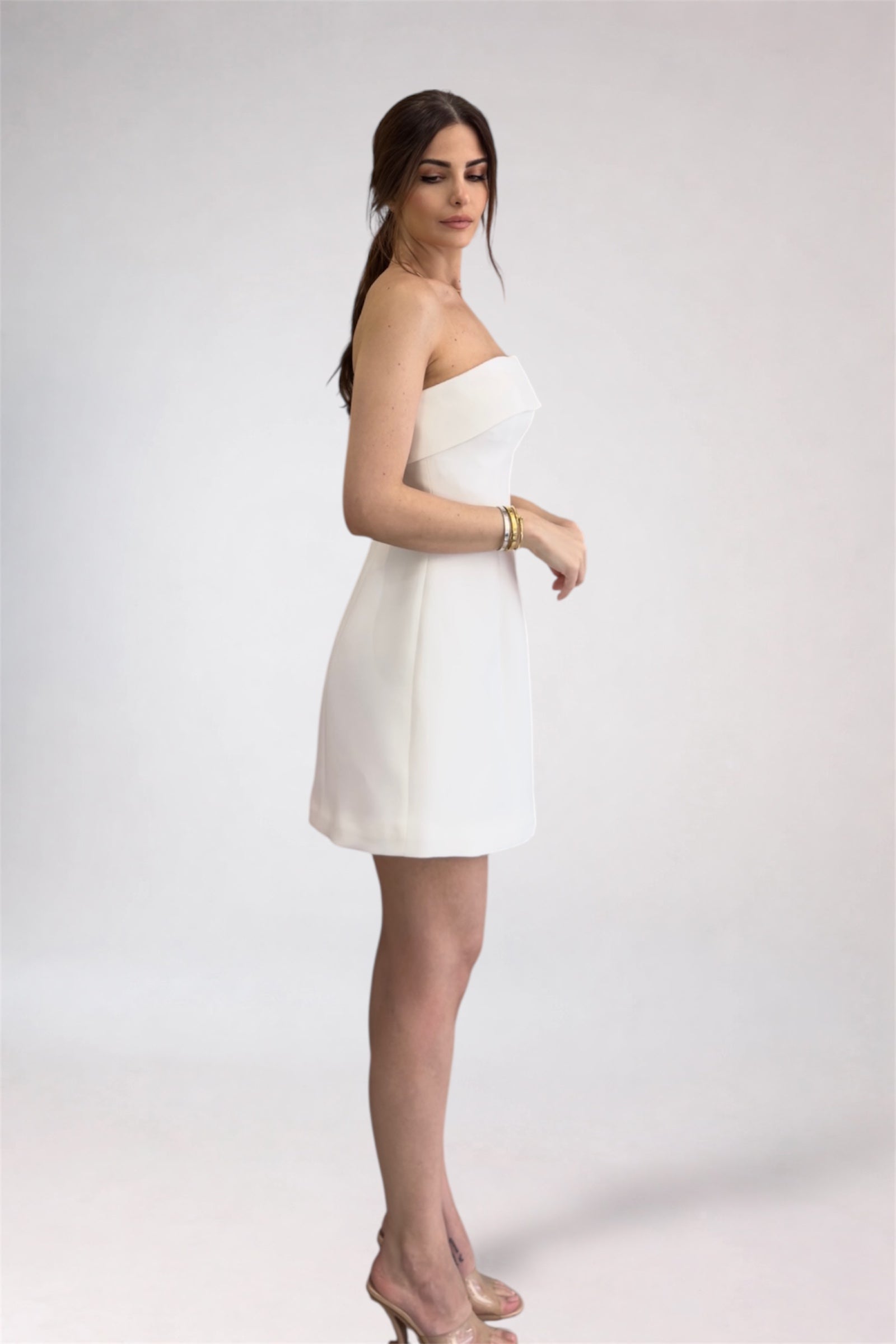 Woman wearing a white strapless dress on a plain background