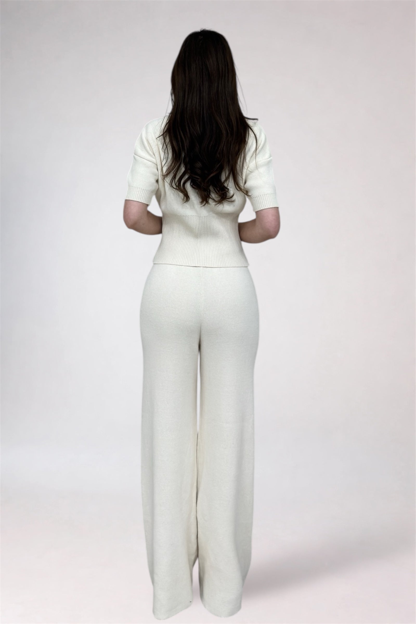 Woman wearing a white outfit against a plain background