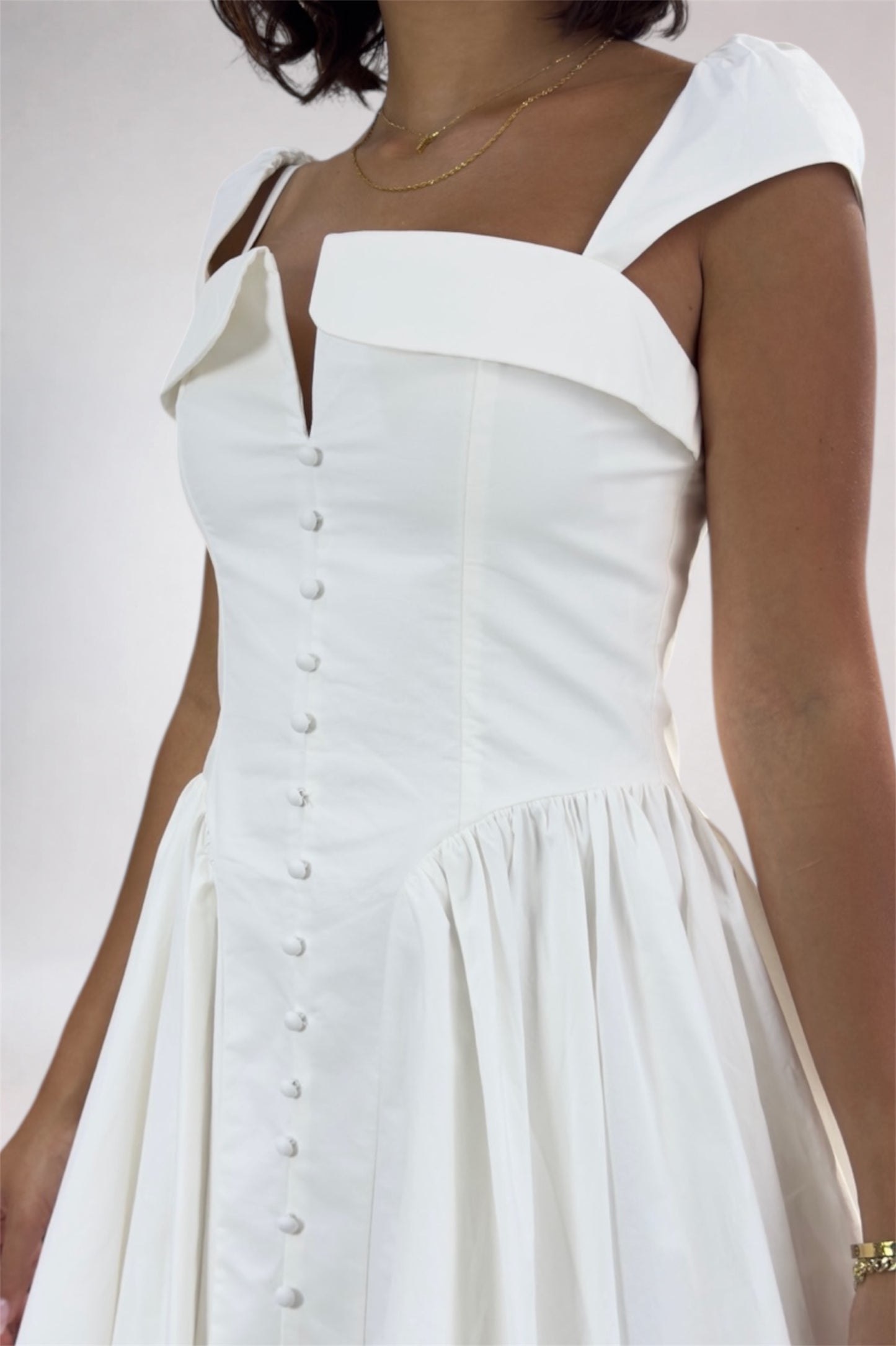 White dress with button details on a plain background