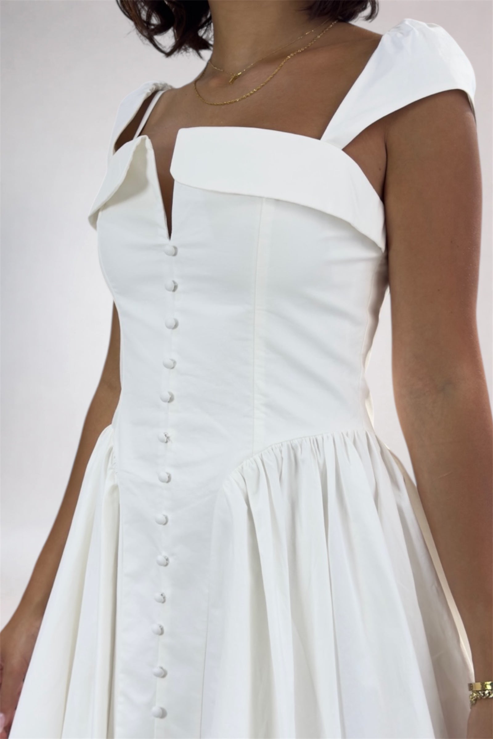 White dress with button details on a plain background