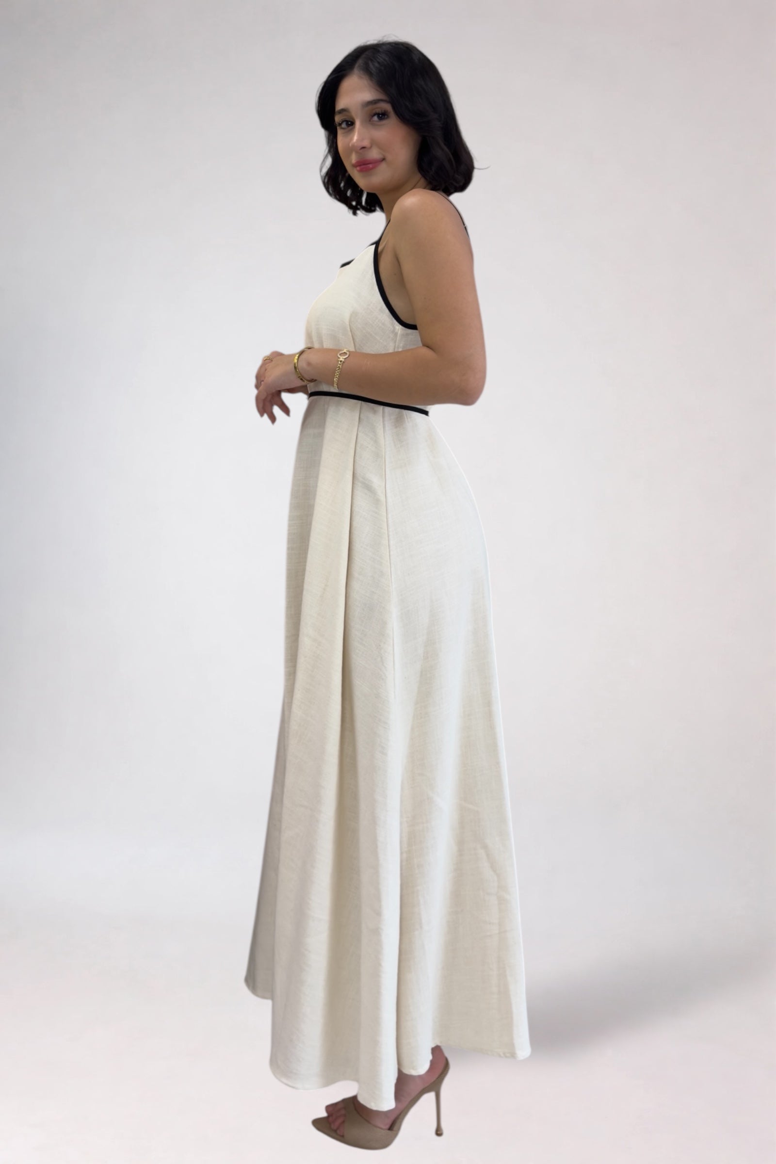 Woman wearing a white dress with black trim on a plain background