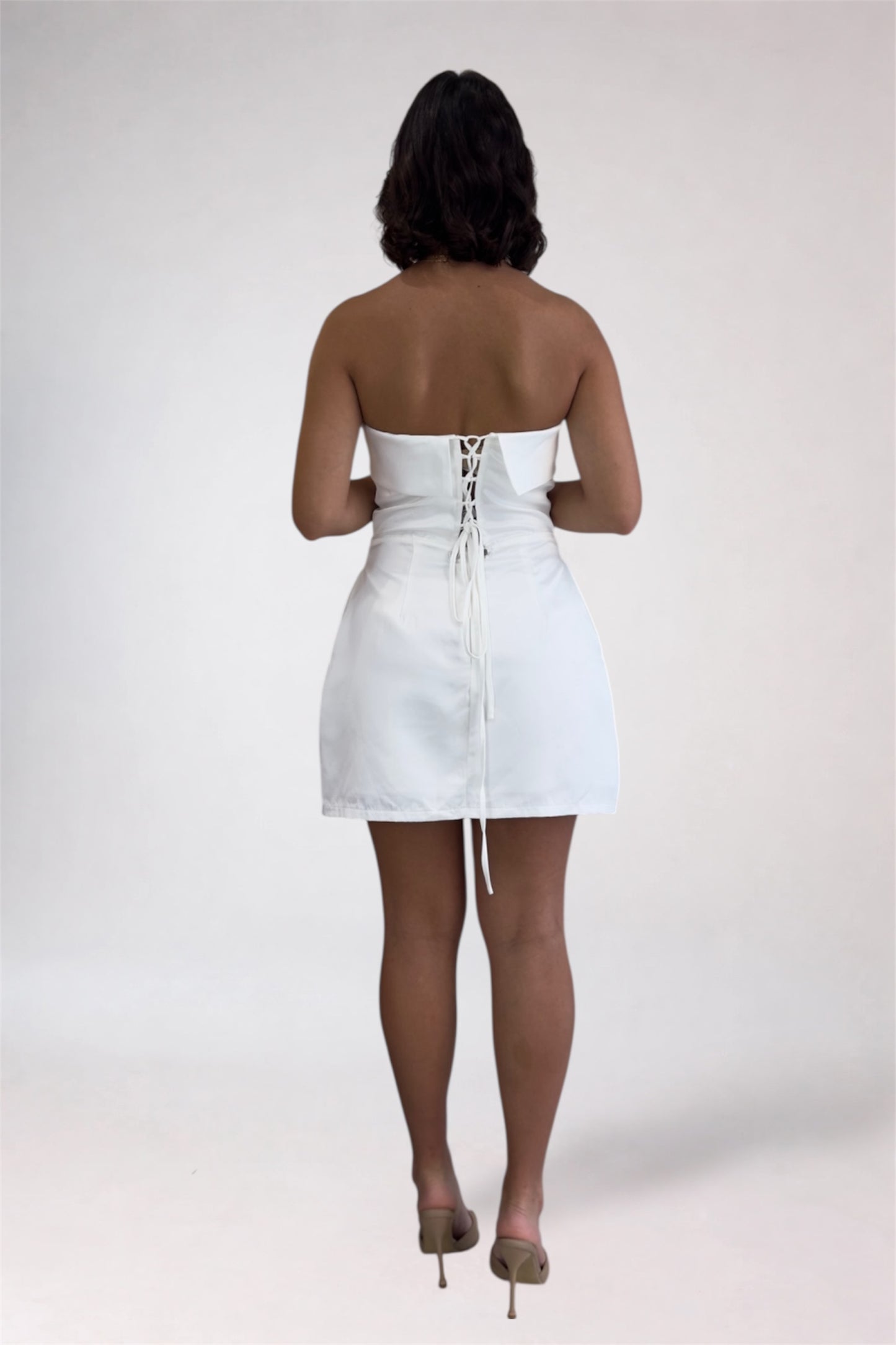 Person wearing a white strapless dress on a plain background