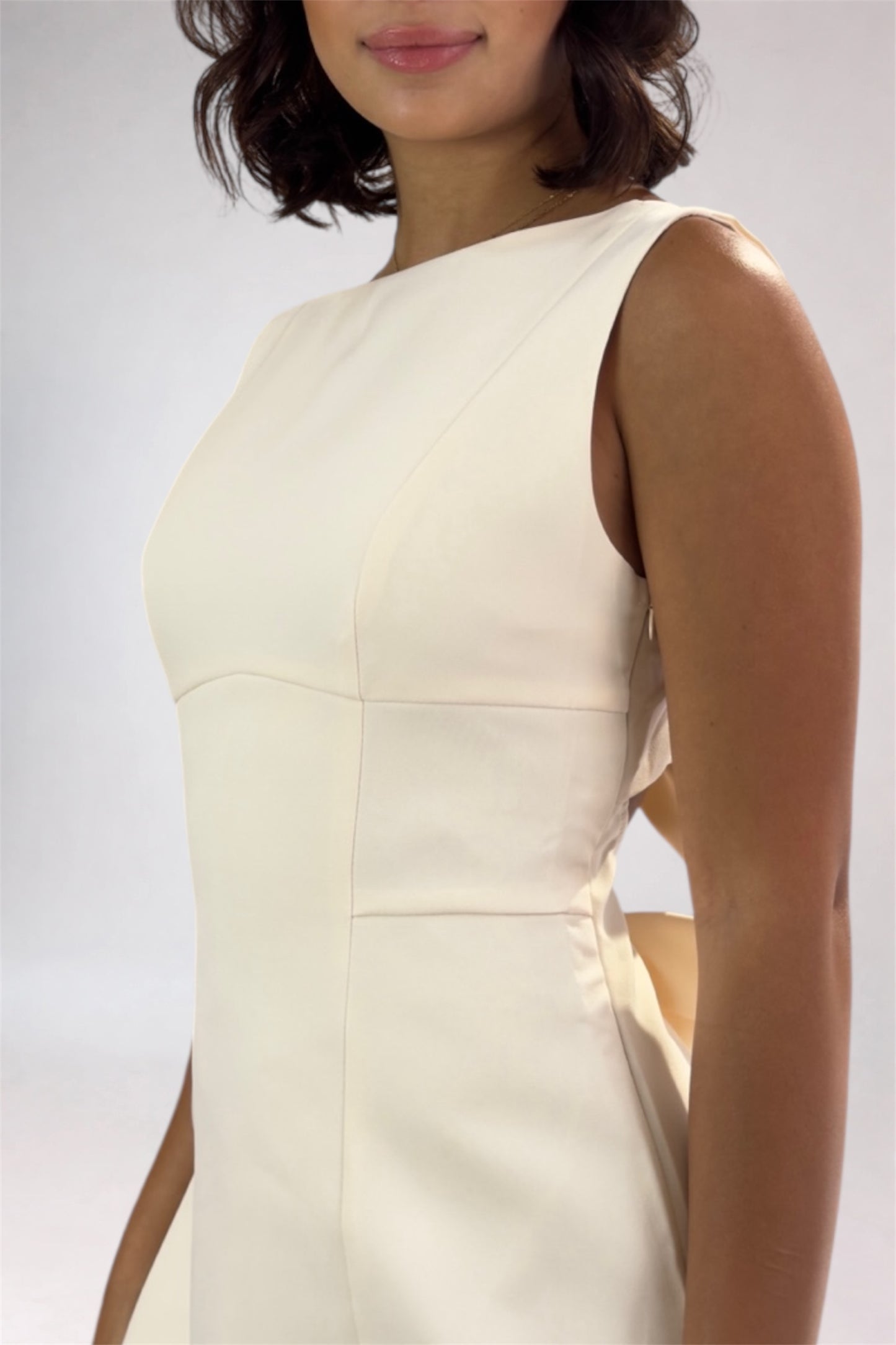 Woman wearing a light-colored dress against a plain background