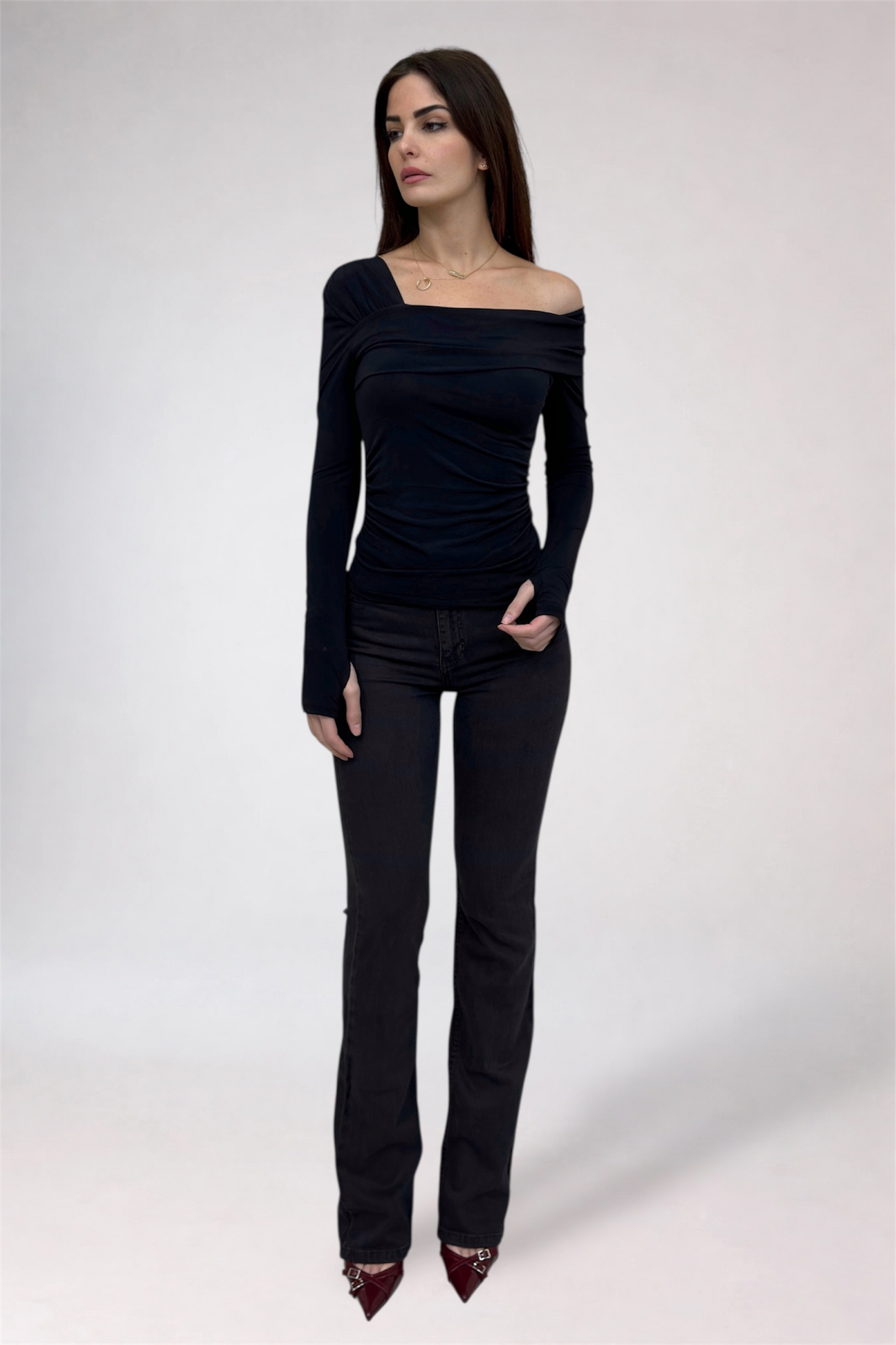 Woman wearing a black off-shoulder top and black jeans on a white background