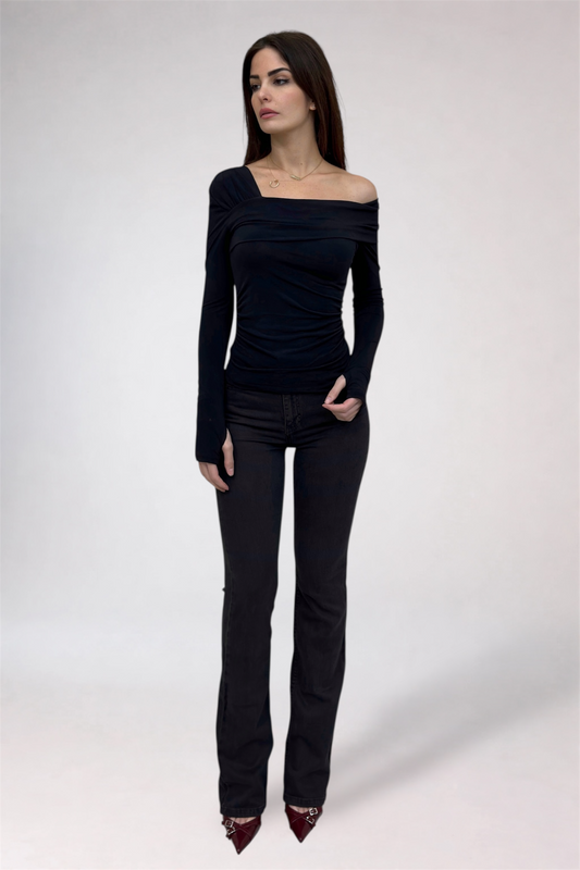 Woman wearing a black off-shoulder top and black jeans on a white background