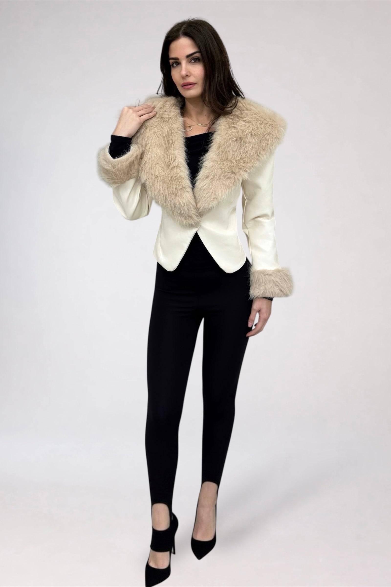 Woman wearing a white jacket with fur collar and black pants on a white background