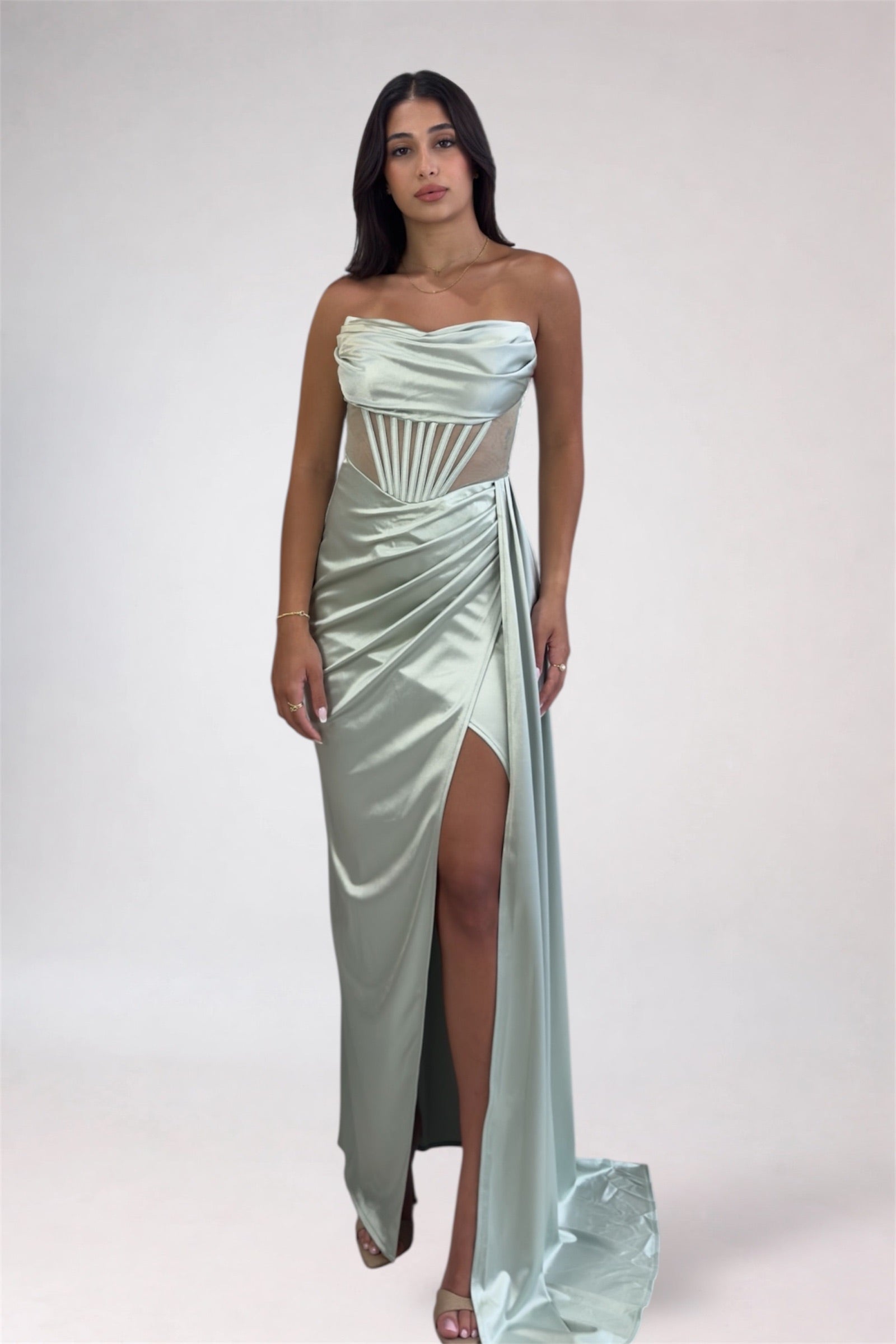 Woman wearing a light blue strapless gown with a high slit on a white background