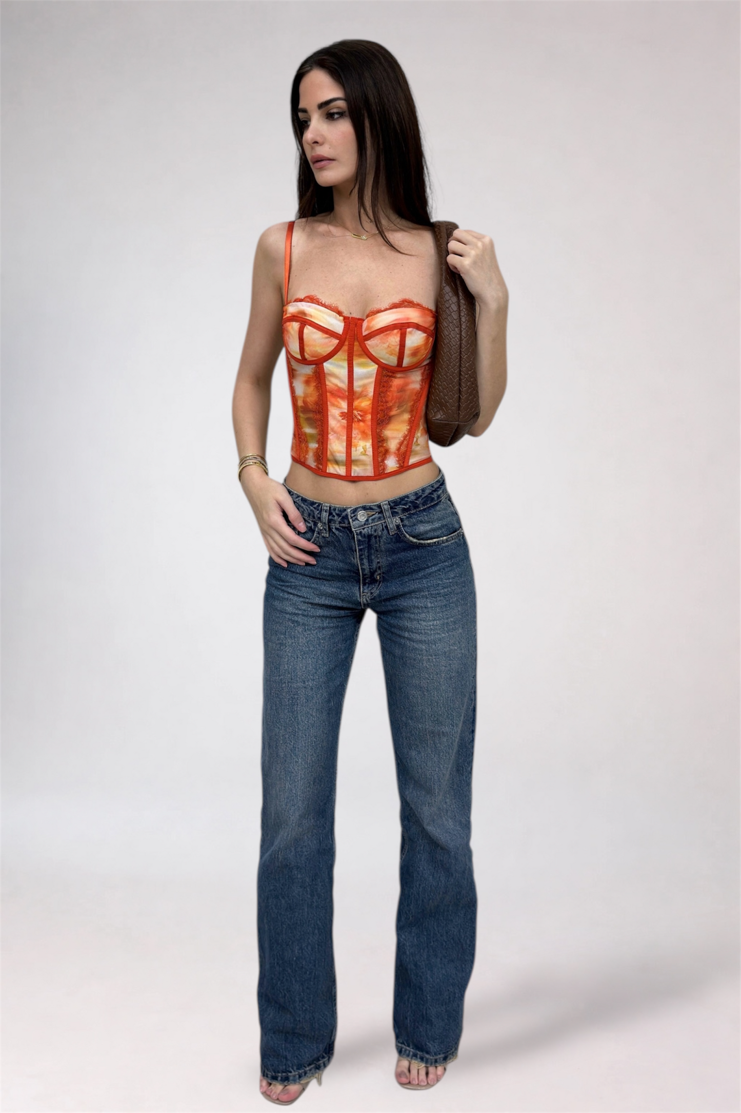 Woman wearing a red top with a unique design and blue jeans on a white background