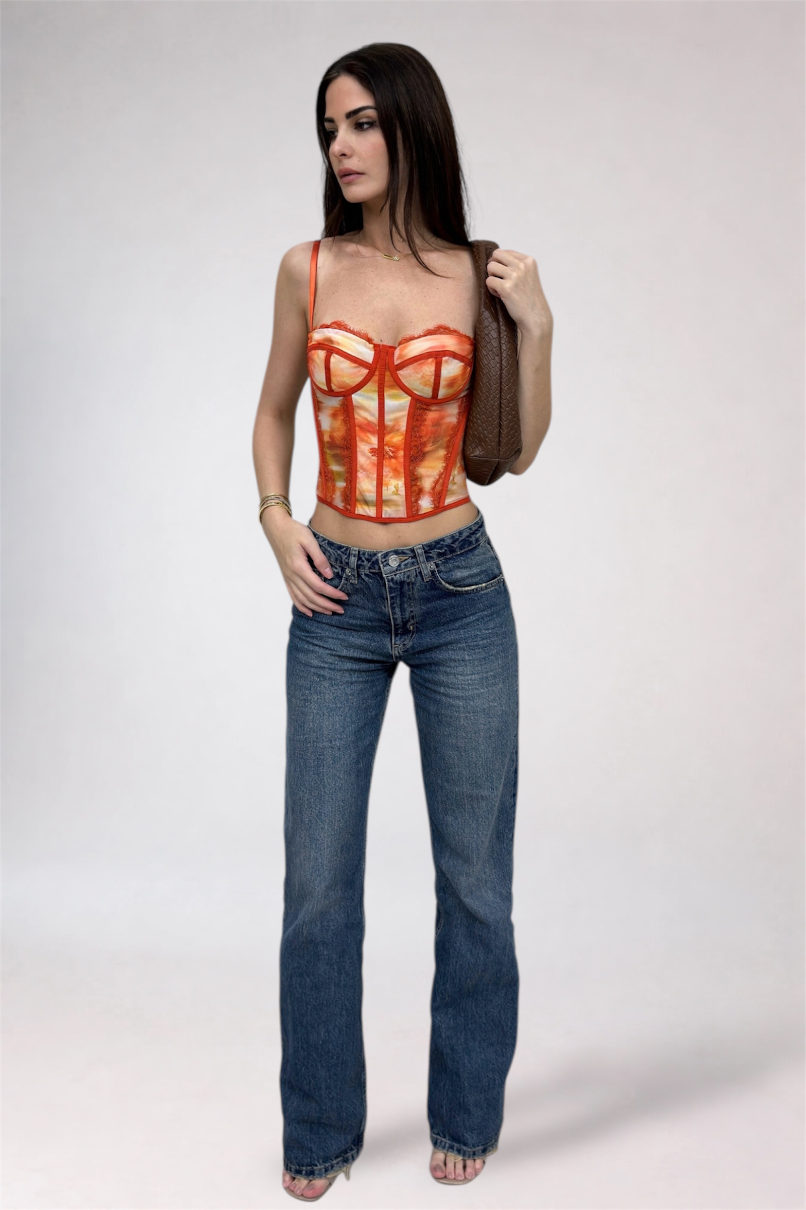 Woman wearing a red top with a unique design and blue jeans on a white background