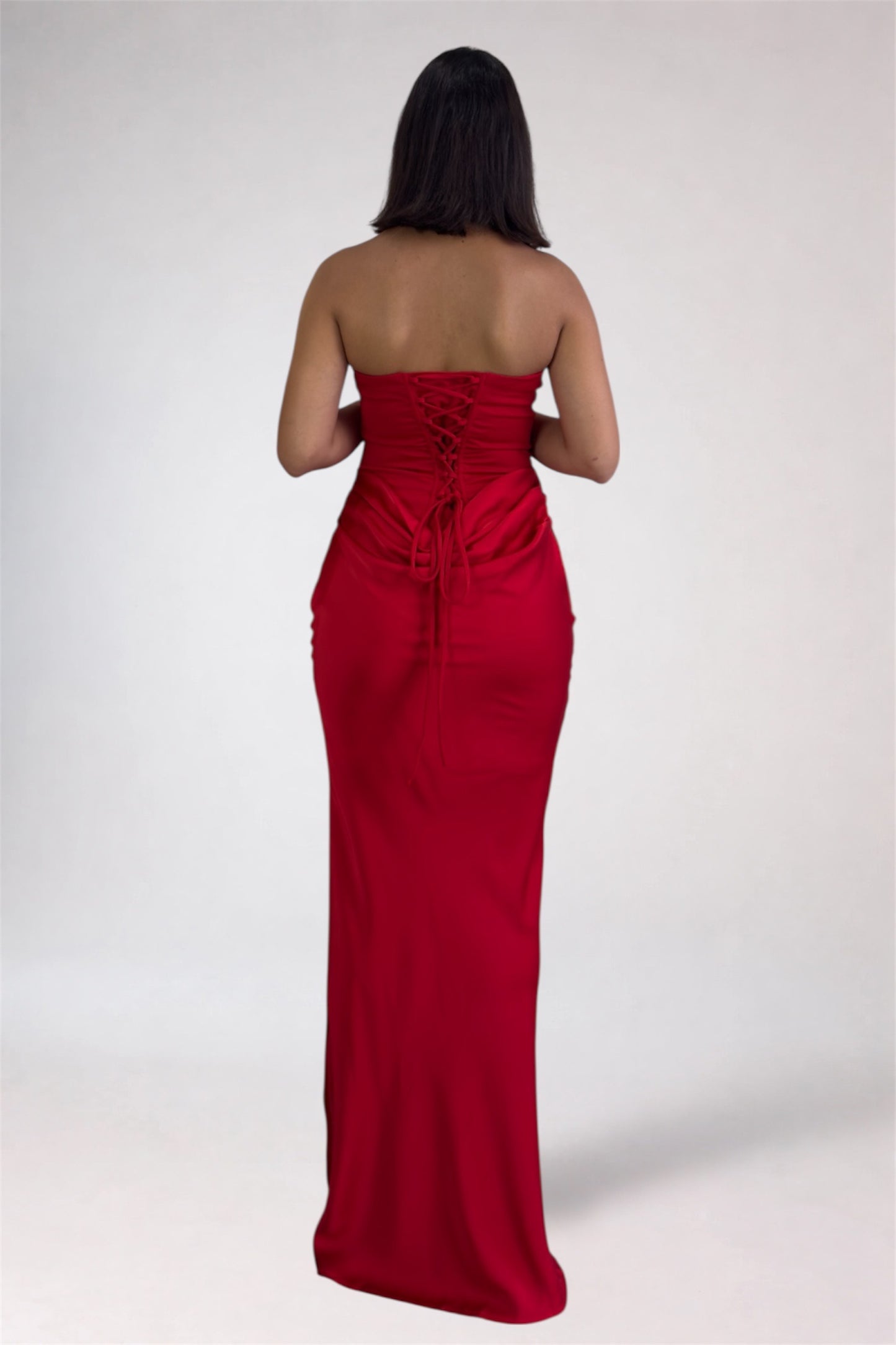 Woman wearing a strapless red evening gown on a white background