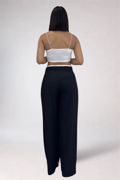Person wearing a white top and black pants on a plain background
